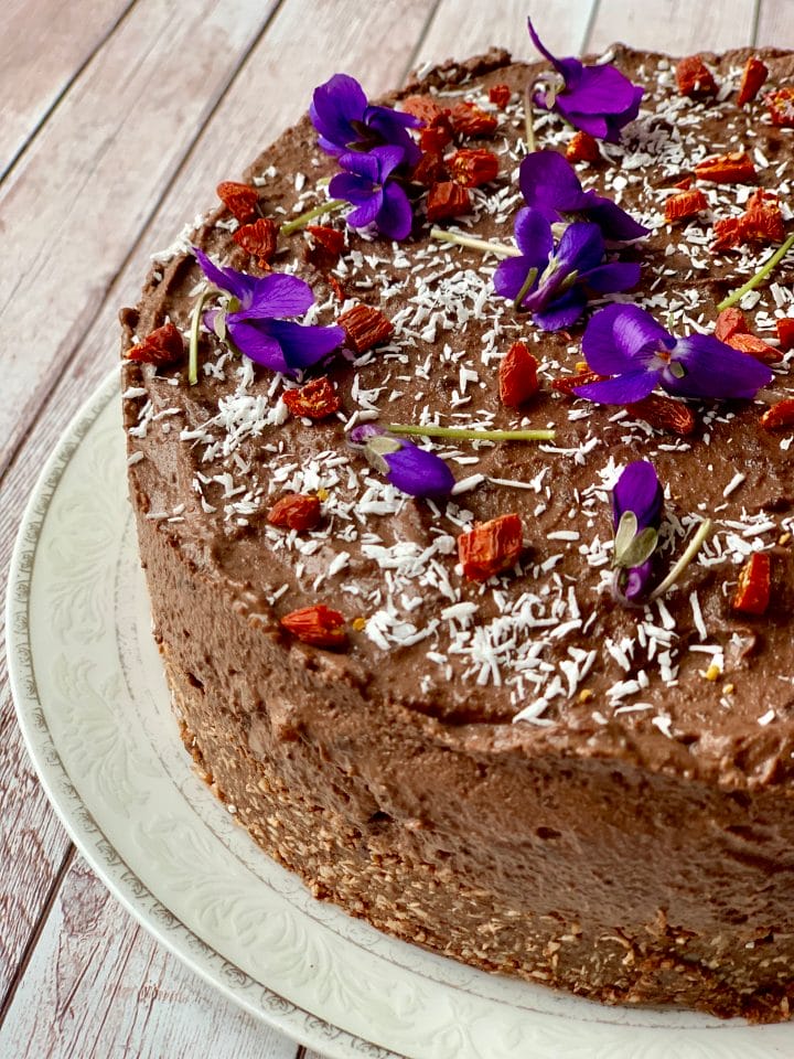 Picture of raw keto chocolate cheesecake with edible flowers
