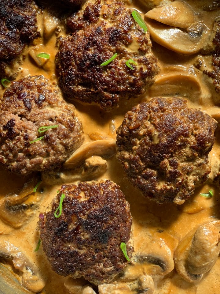 Picture of keto salisbury steaks in mushroom gravy with chopped spring onion on top