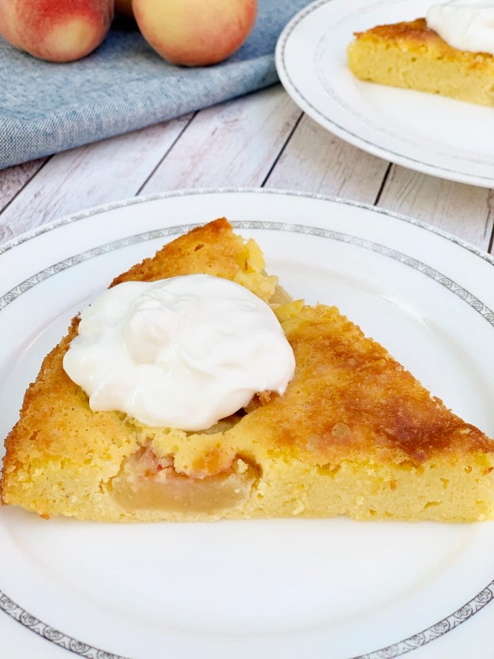 Peach keto cake slice on a table with sour cream on top.