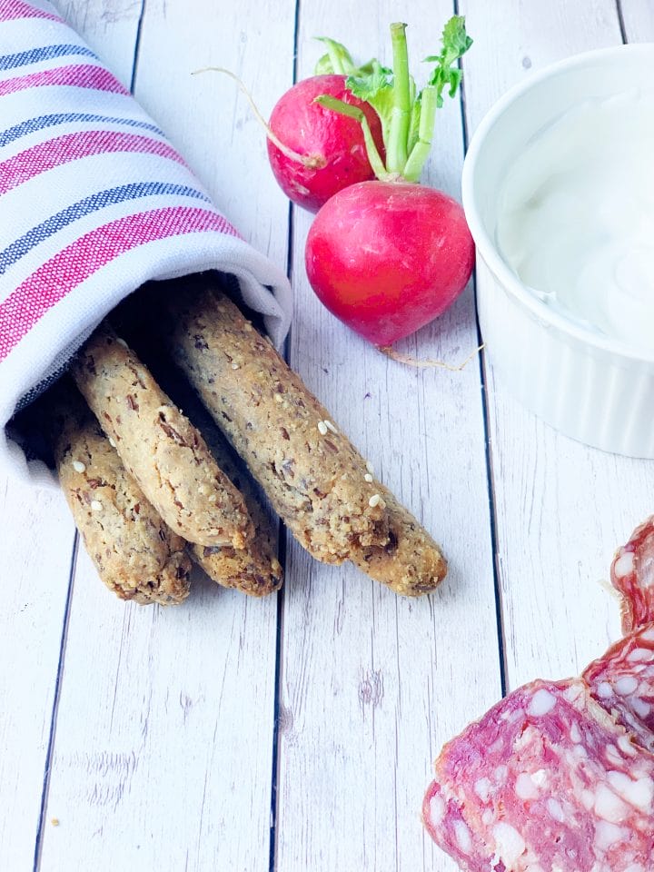 Image of low carb Italian grissini with sour cream dip and dried sausages