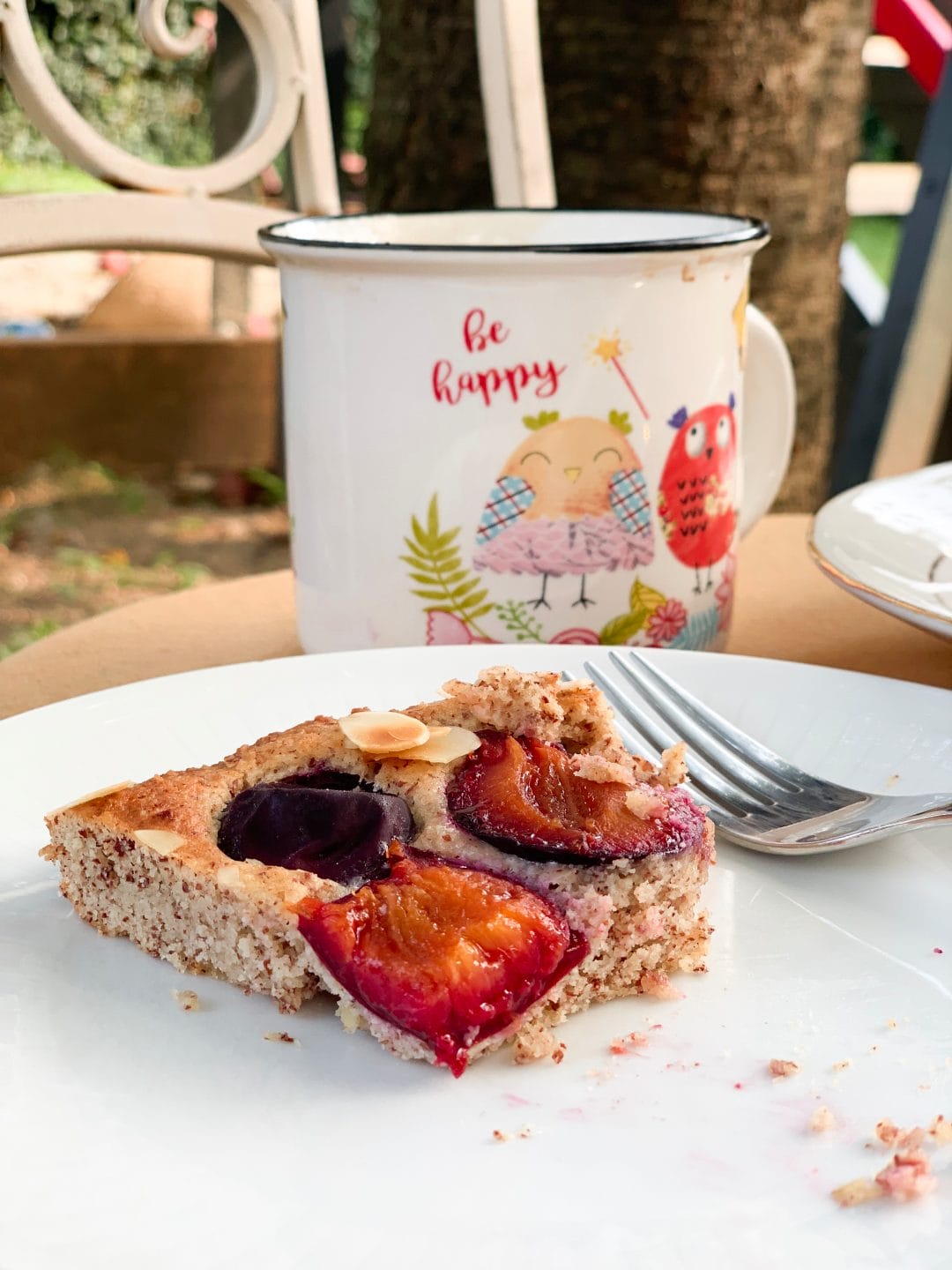 Picture of a slice of lchf plum pie on a table in the garden