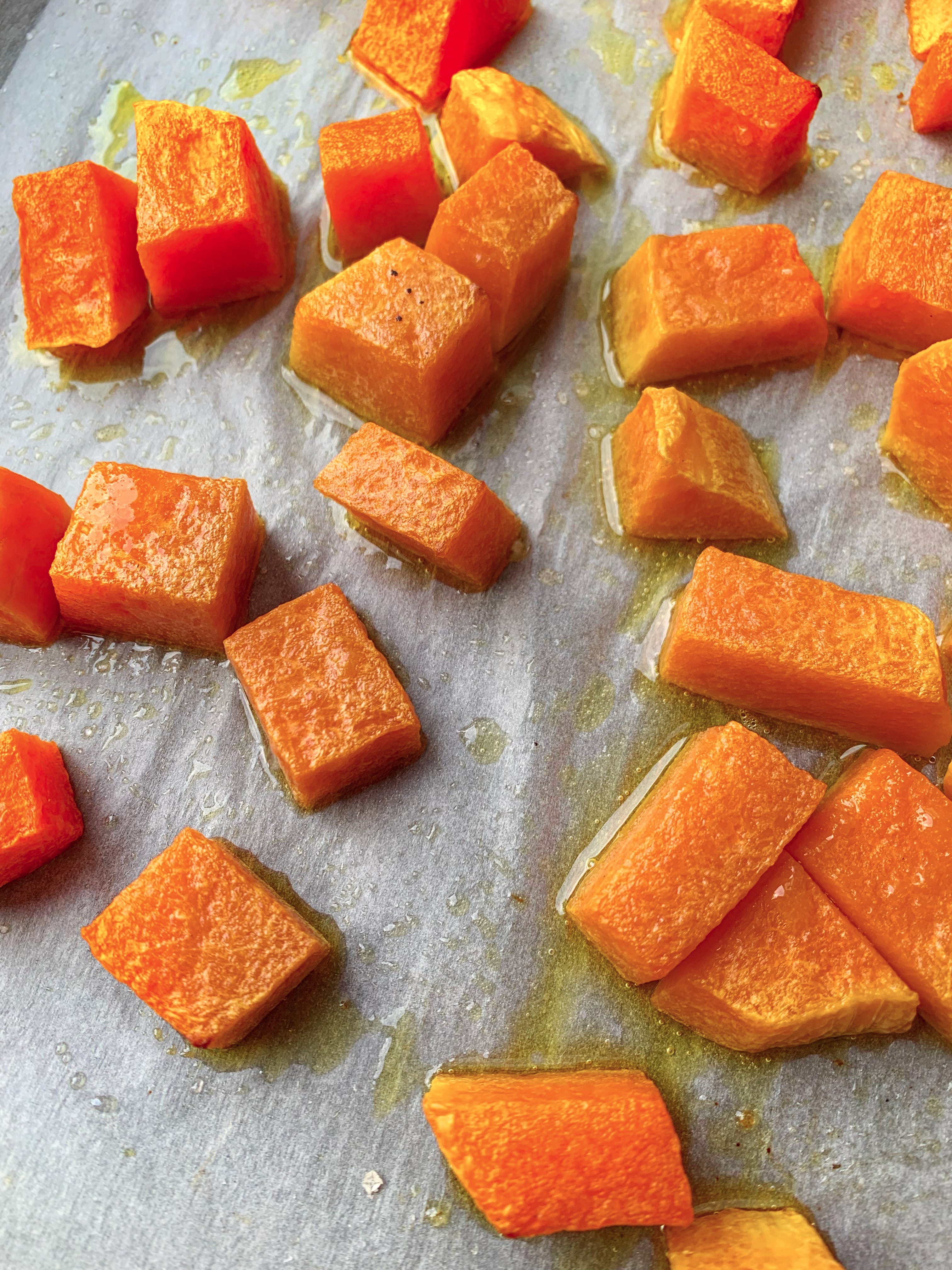Picture of roasted pumpkin on a parchment paper with olive oil and coarse salt