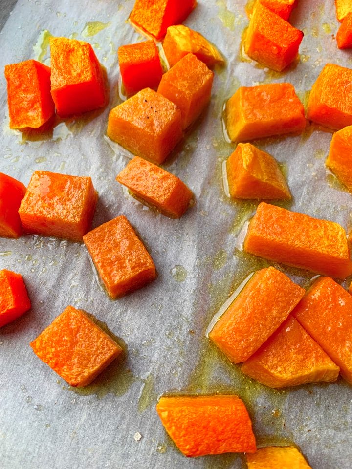 Picture of roasted pumpkin on a parchment paper with olive oil and coarse salt