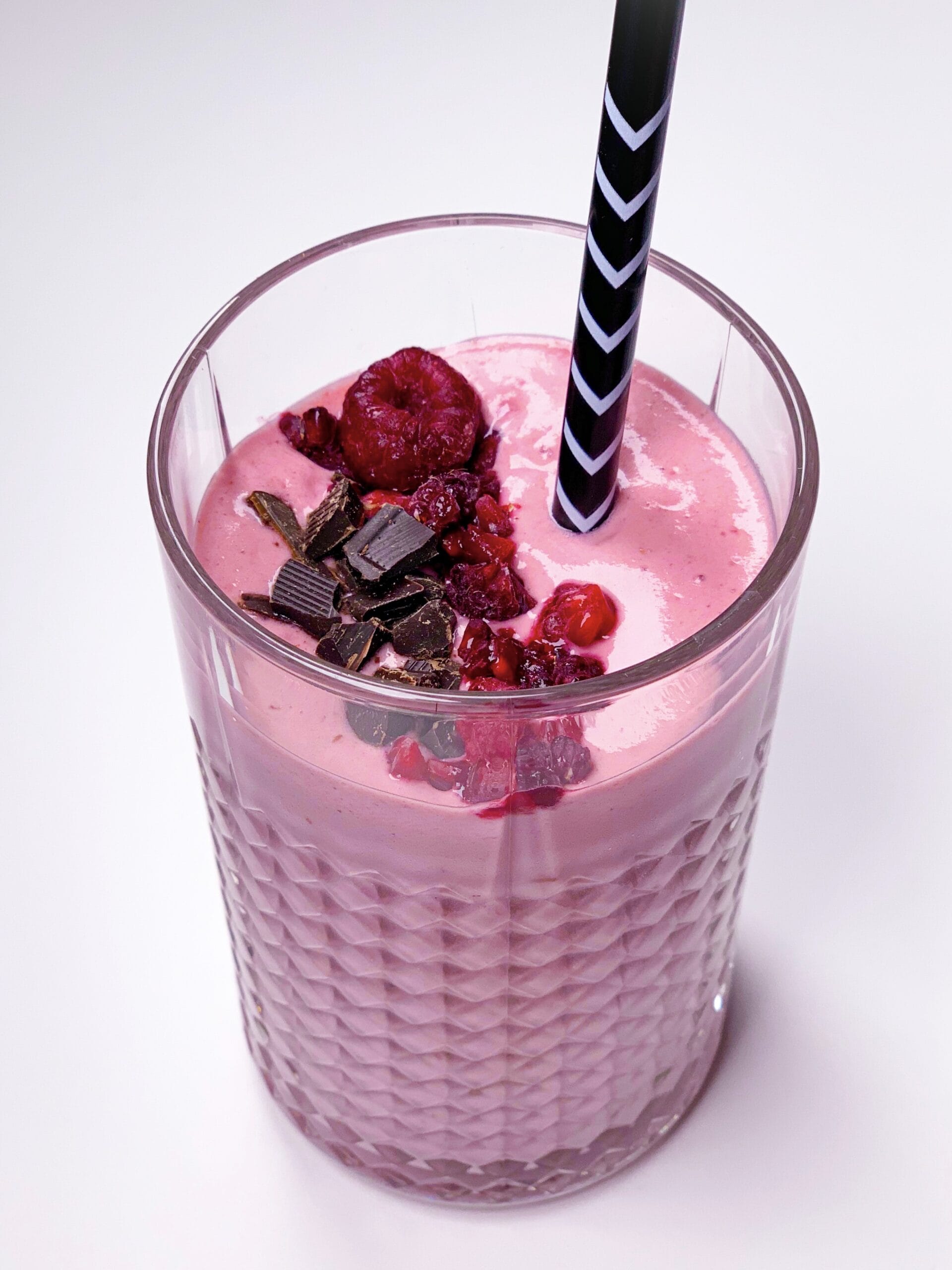 Glass of low carb smoothie with frozen raspberries and chocolate protein powder