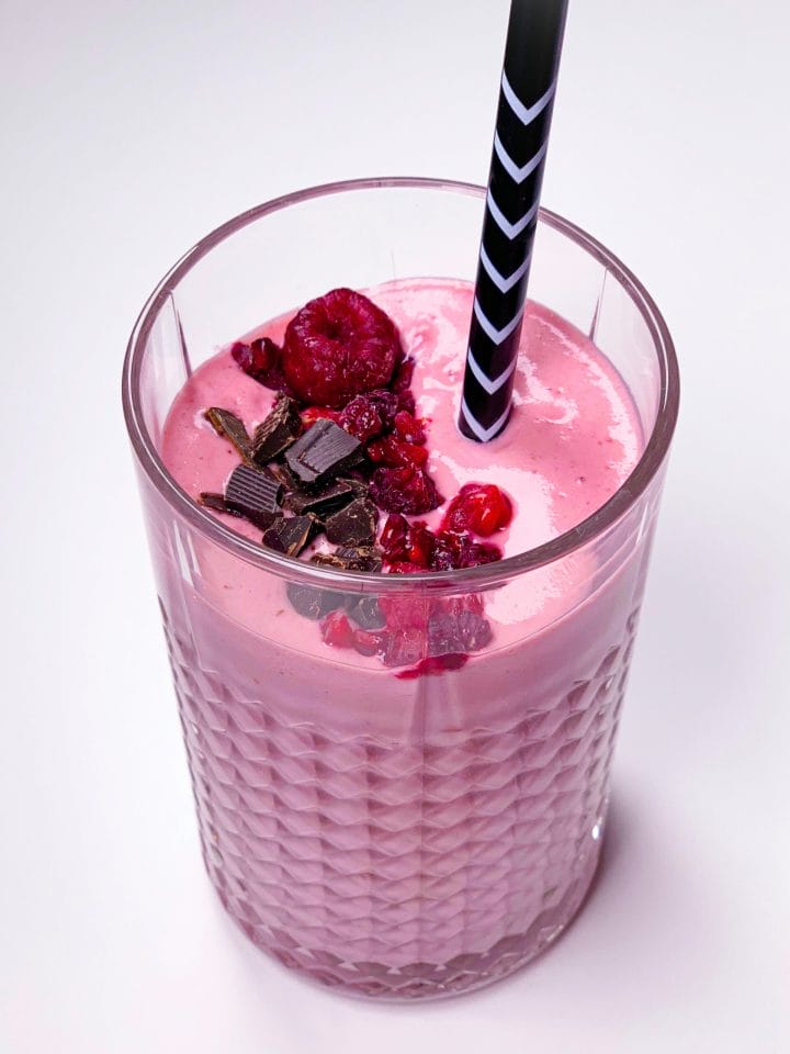 Glass of low carb smoothie with frozen raspberries and chocolate protein powder