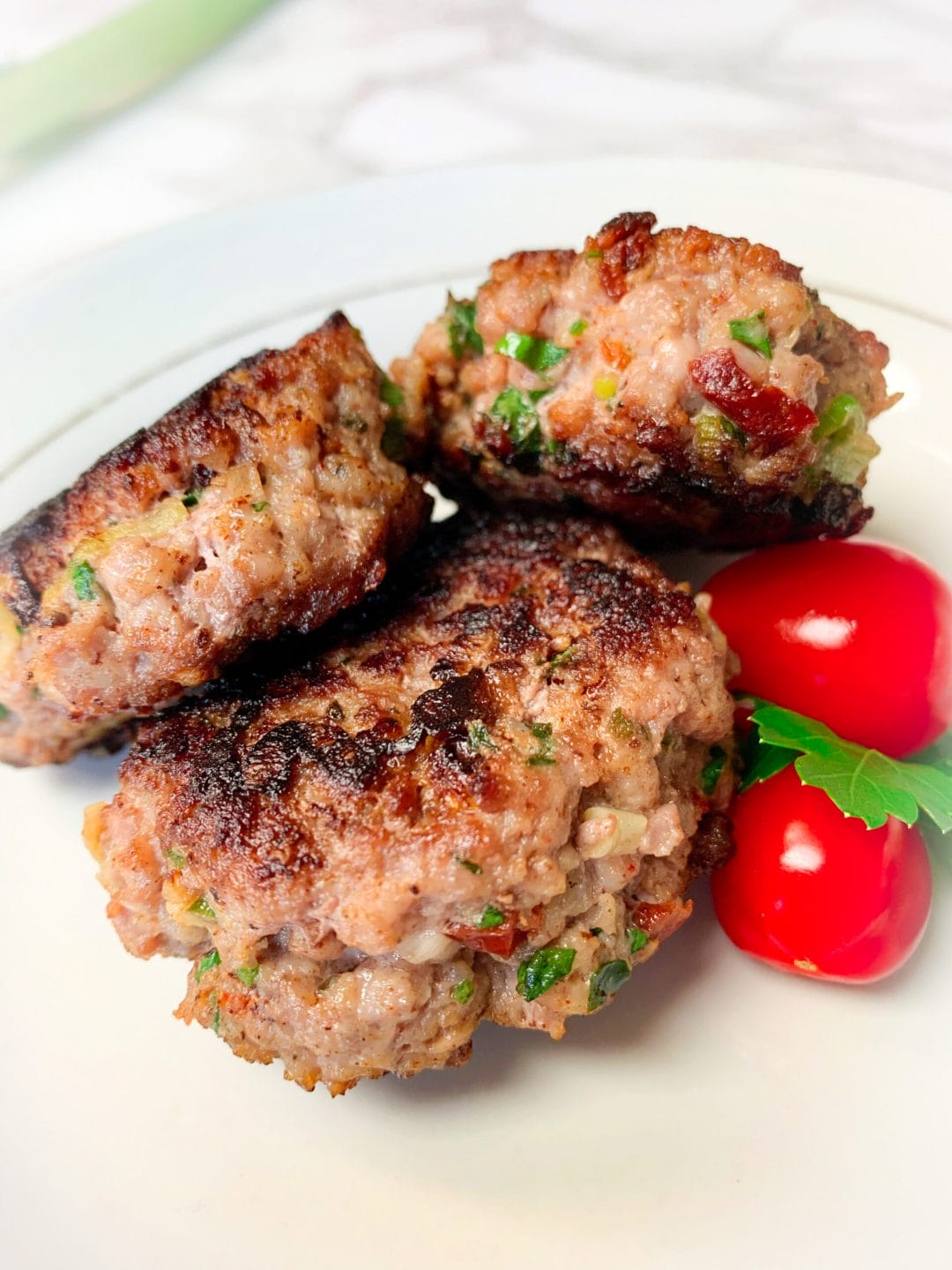 Picture of keto breakfast sausage patties on a plate with cherry tomatoes