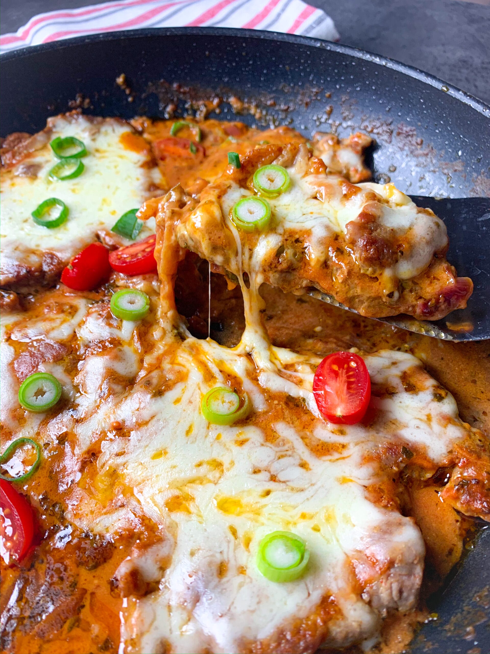 Picture of cooked pork neck steak in tomato sauce with melted mozzarella on top