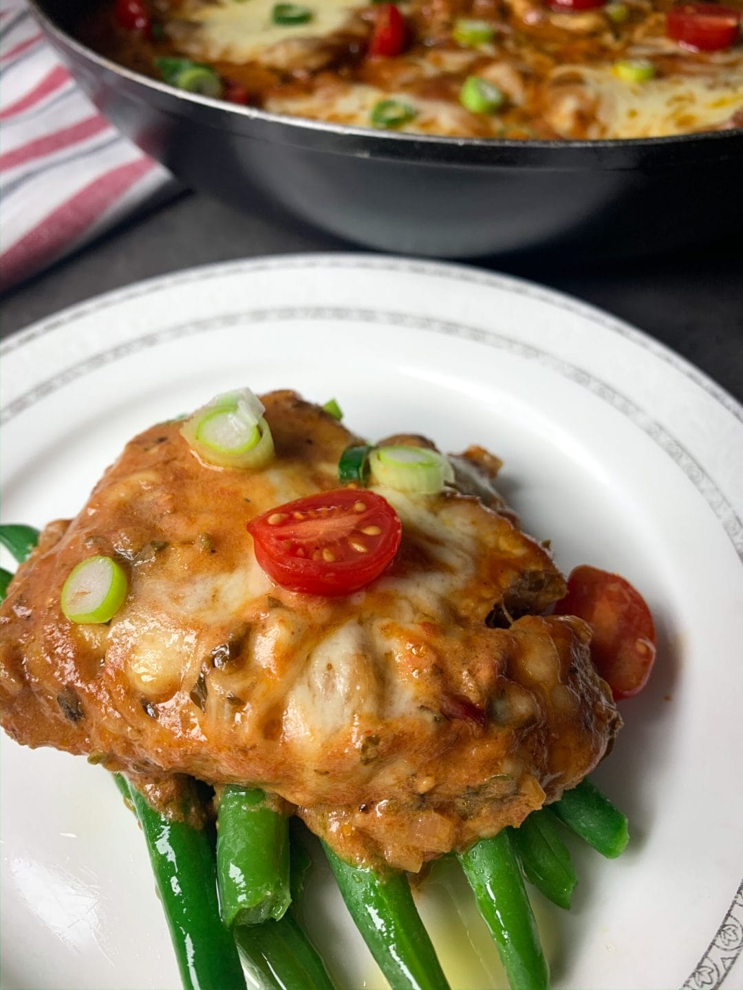 Picture of a plate with green beans and pork neck with melted cheese on top