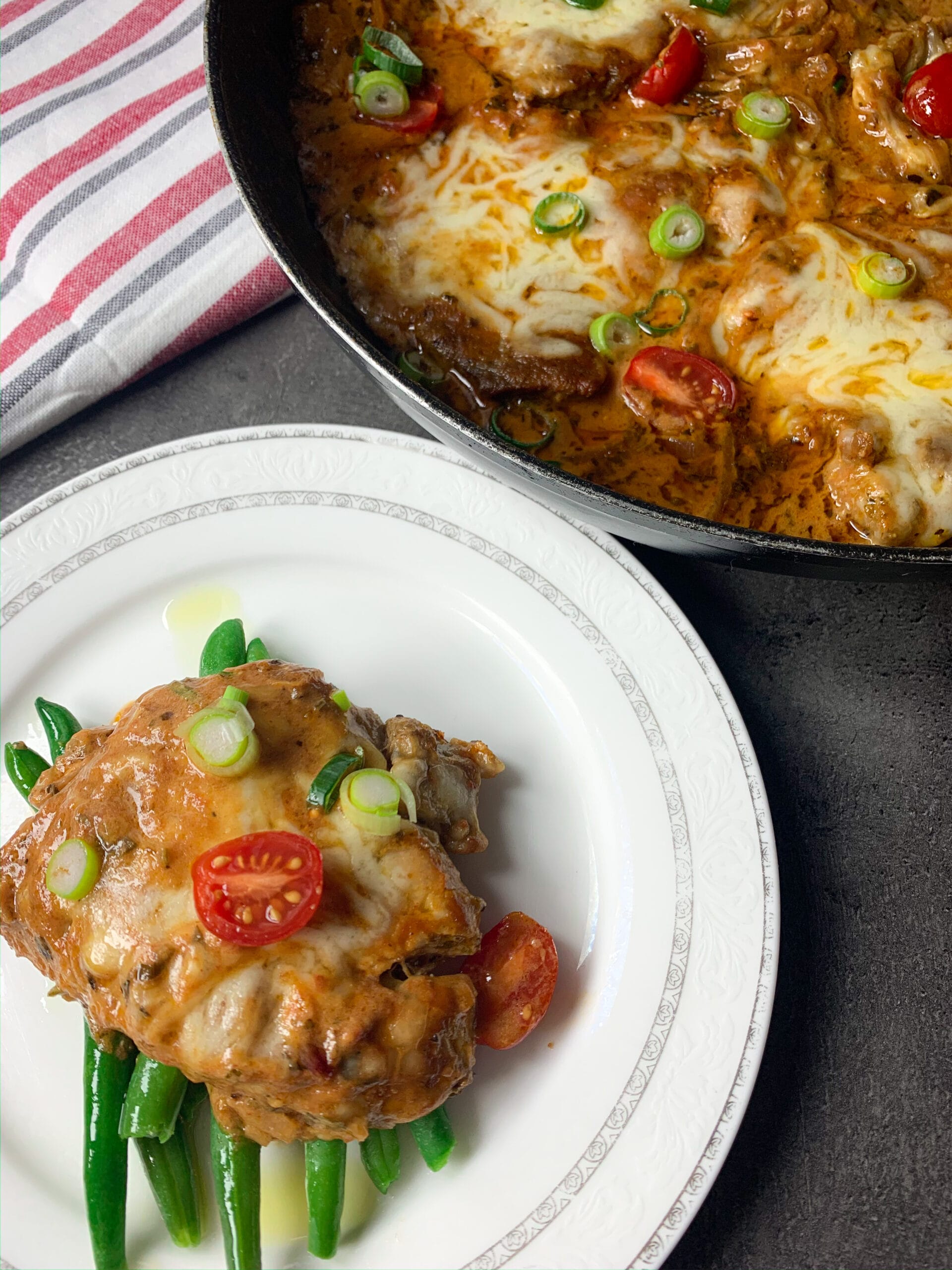 Pork neck in tomato sauce served on a plate as a keto meal with cooked green beans