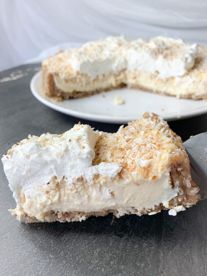 Slice of low carb coconut cream pie with heavy whipping cream on top