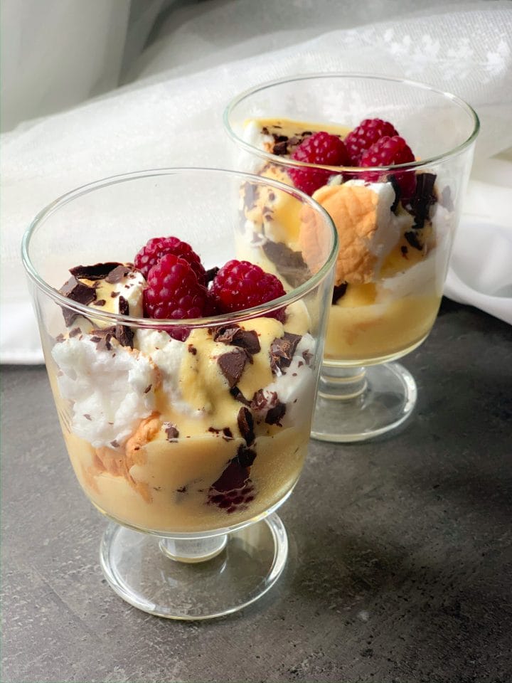 Berry meringue keto desserts with custard cream, whipped cream, chocolate shavings and raspberries