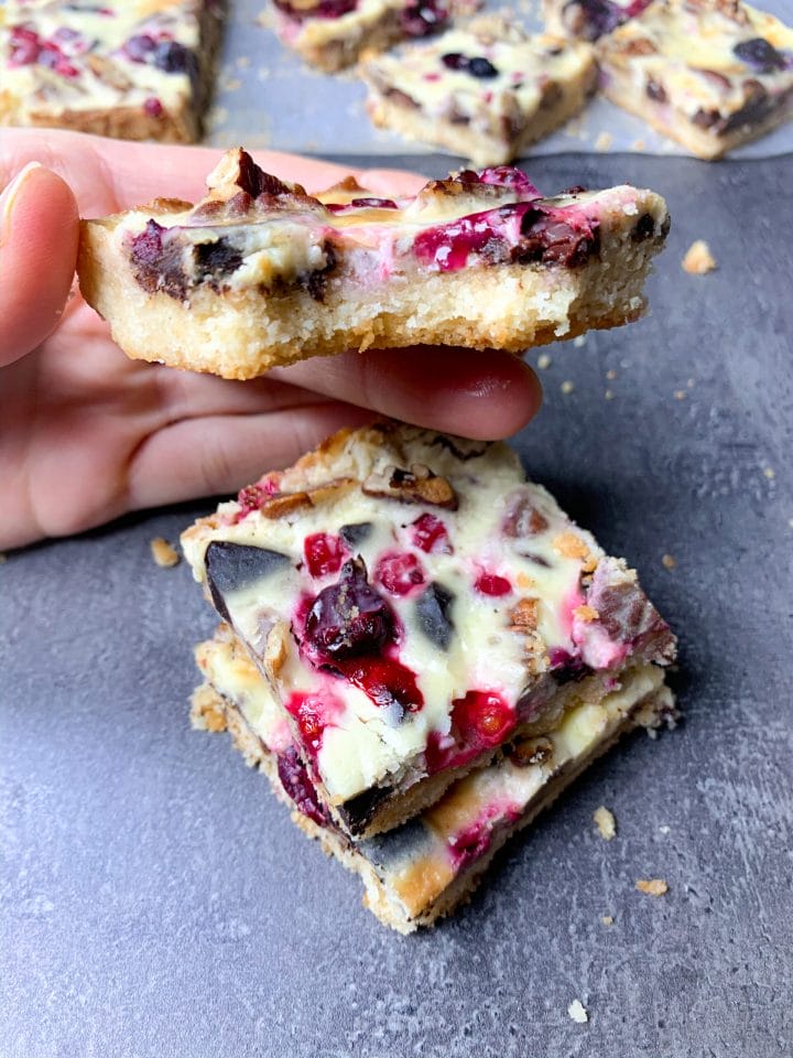 Picture of low carb magic cookie bars with pecans, chocolate and berries topped with delicious keto condensed milk cream