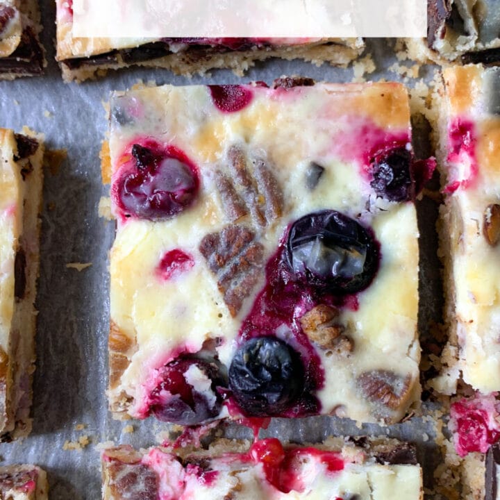 Photo of keto magic cookie bars with berries, pecans and dark chocolate and condensed keto milk cream