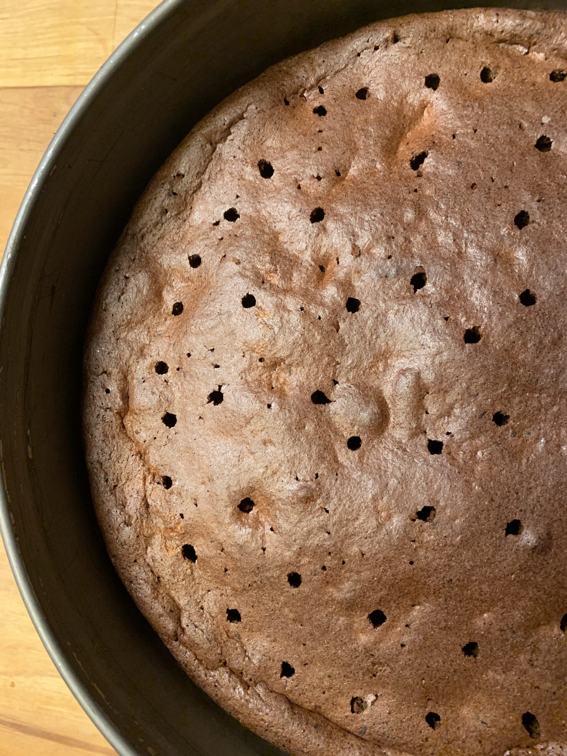Picture of poked flourless chocolate cake. Instruction how to poke a cake with a straw.
