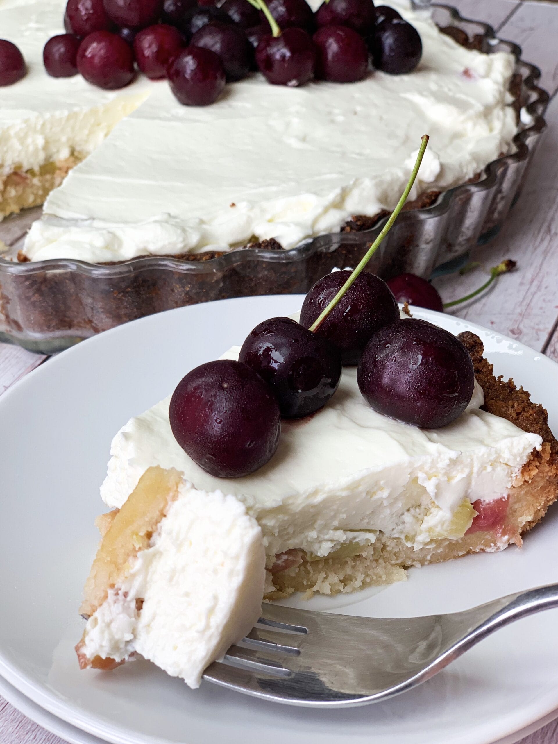 Piece of low carb rhubarb cheesecake with low carb pie crust and cherries on top