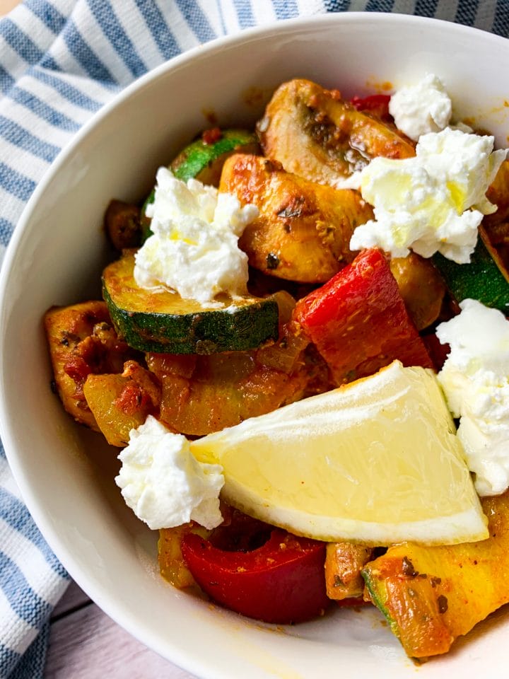 Picture of a bowl of chicken with vegetables and feta cheese on top