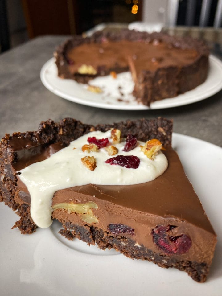 Photo of a slice of low carb chocolate ganache tart with dried fruit and pecan