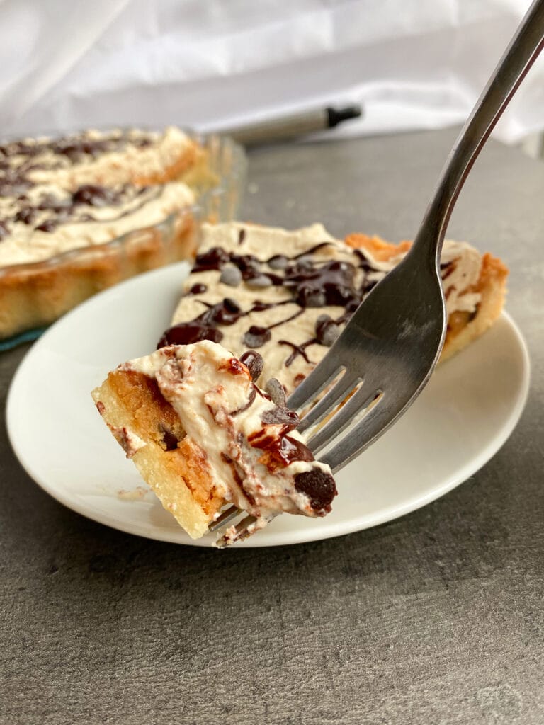 Picture of a piece of low carb peanut butter cookie dough pie with cream topping on a fork