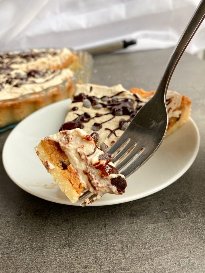 Picture of a piece of low carb peanut butter cookie dough pie with cream topping on a fork