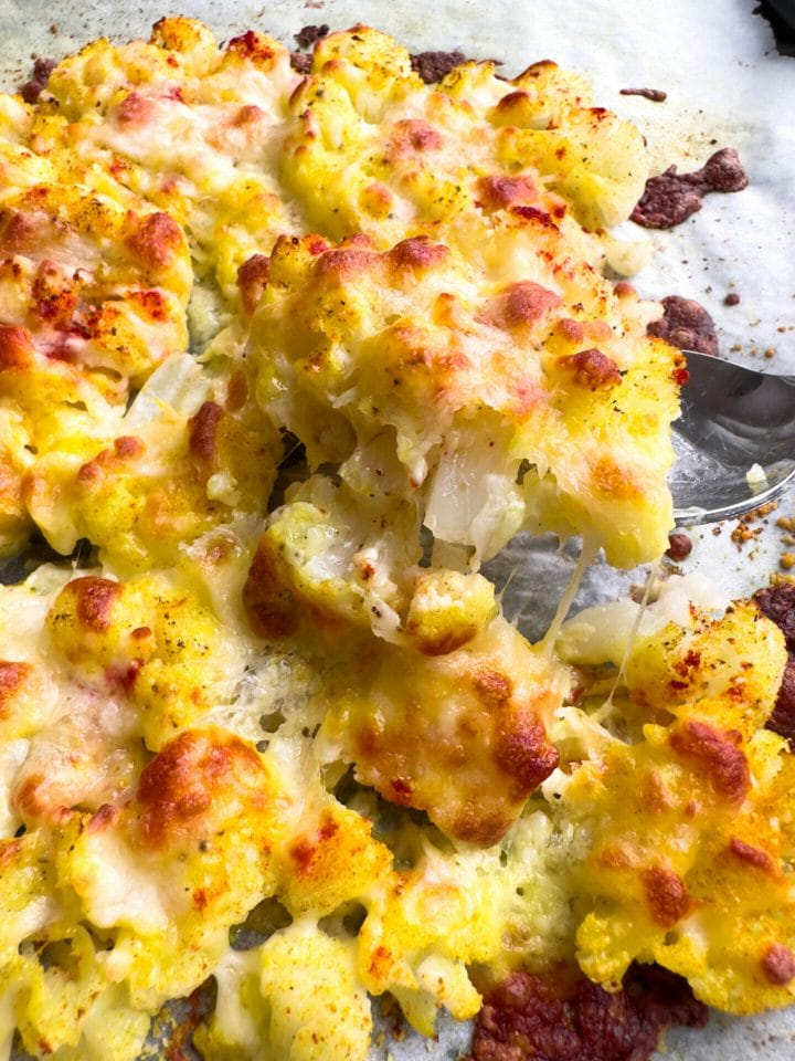 Picture of a baking sheet with roasted cauliflower with melted cheese on top